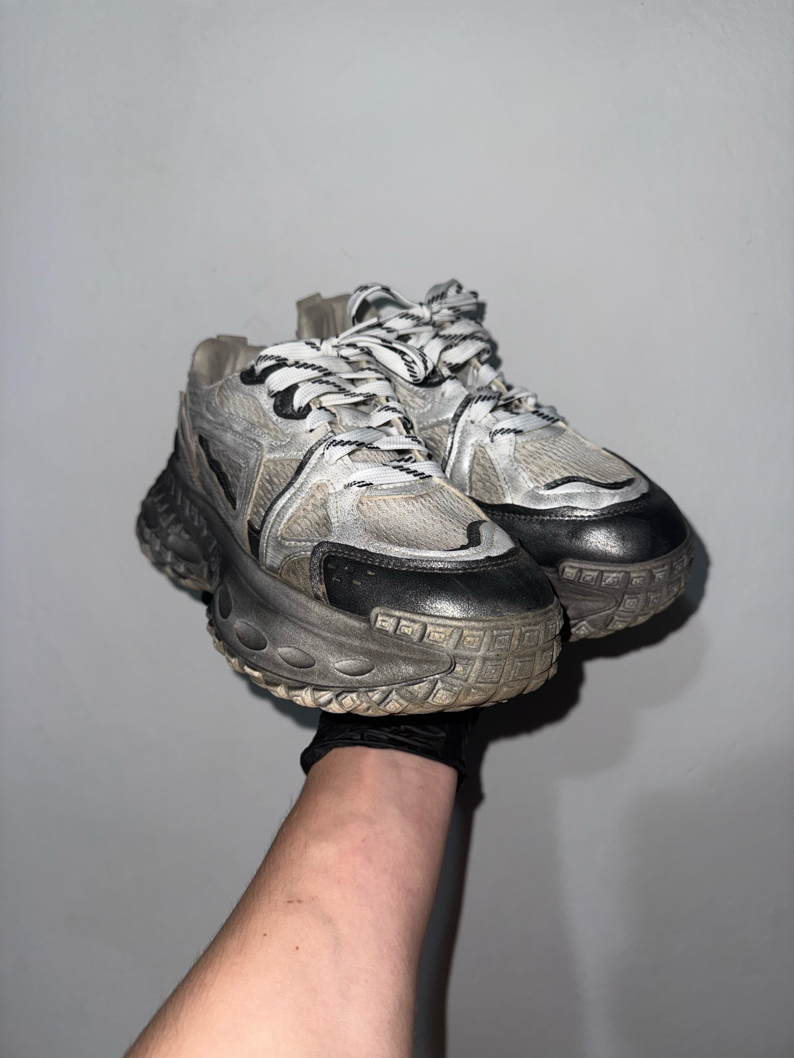 Person holding a worn-out sneaker against a plain background