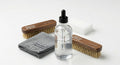 Set of shoe care products including brushes and a bottle on a white background